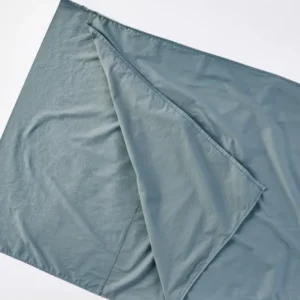 Coyuchi Cloud Soft Sateen Travel Sack in slate blue, folded flat showing interior lining.