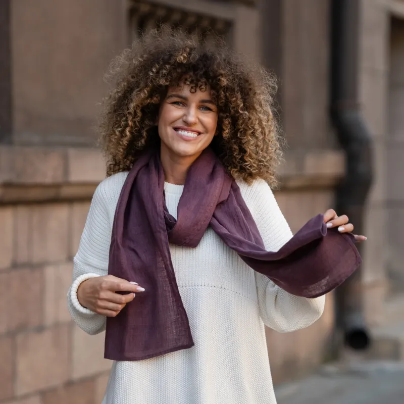 Elegant plum-colored European washed linen scarf draped over white knit sweater showing lightweight fabric texture by Menique