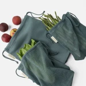 Coyuchi Conserve produce bag set in slate, styled with fresh peaches and vegetables.