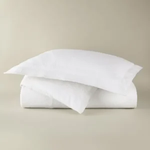 Peacock Alley Montauk Matelassé duvet cover in white with textured weave, folded with pillow sham.