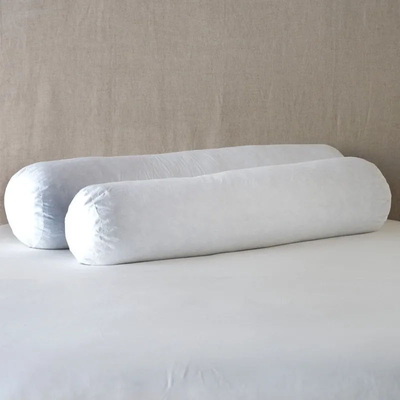 Bella Notte Essential Down bolster pillow inserts in white, pair styled on a made bed.