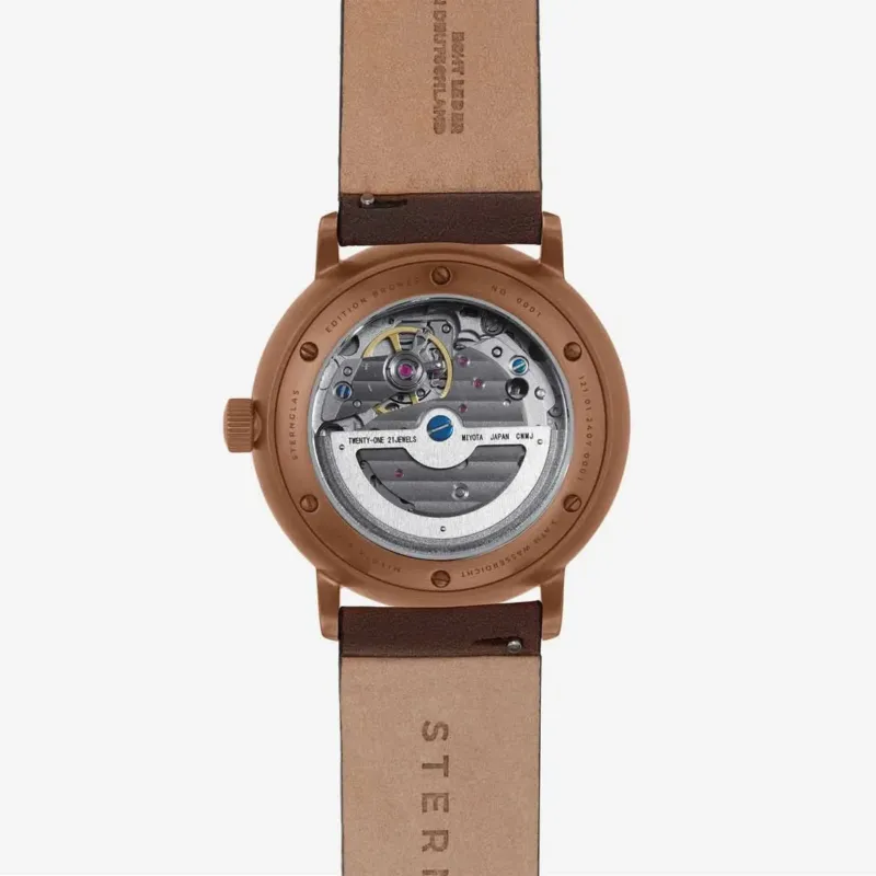 Herrenuhr Rückseite: sichtbares Uhrwerk, braunes Lederband, bronzefarbener Gehäuseboden.