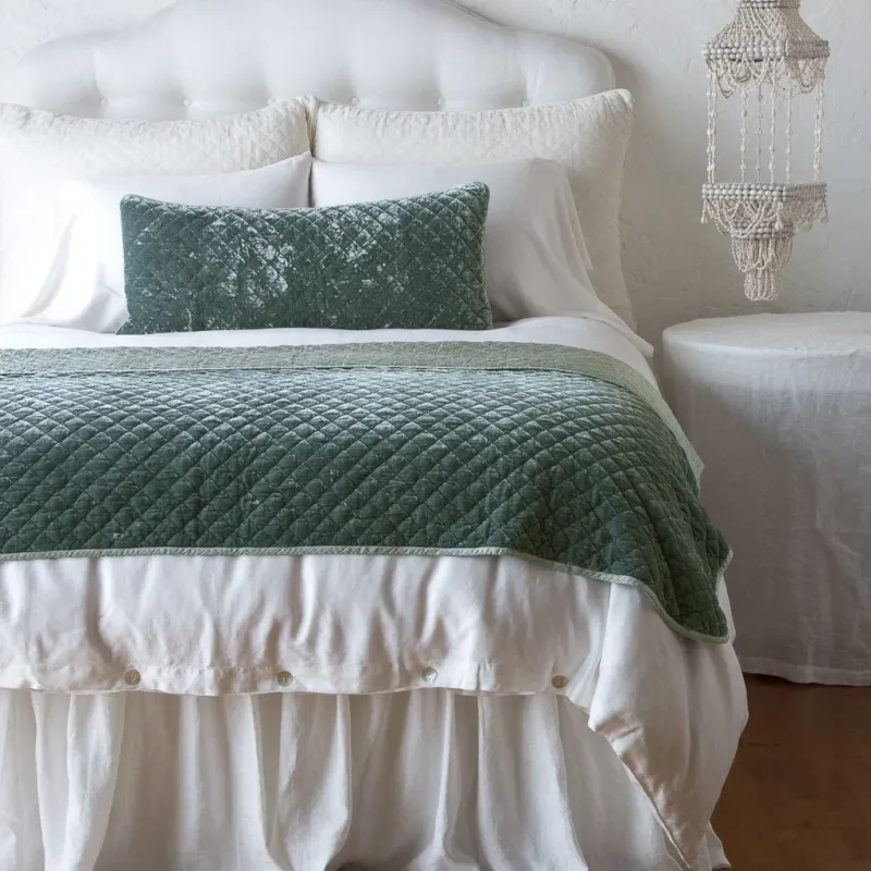 Eucalyptus silk velvet quilted throw pillow styled on a bed with matching quilt.