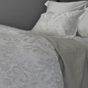 SDH Baton Rouge white damask jacquard duvet cover and shams on a made bed.