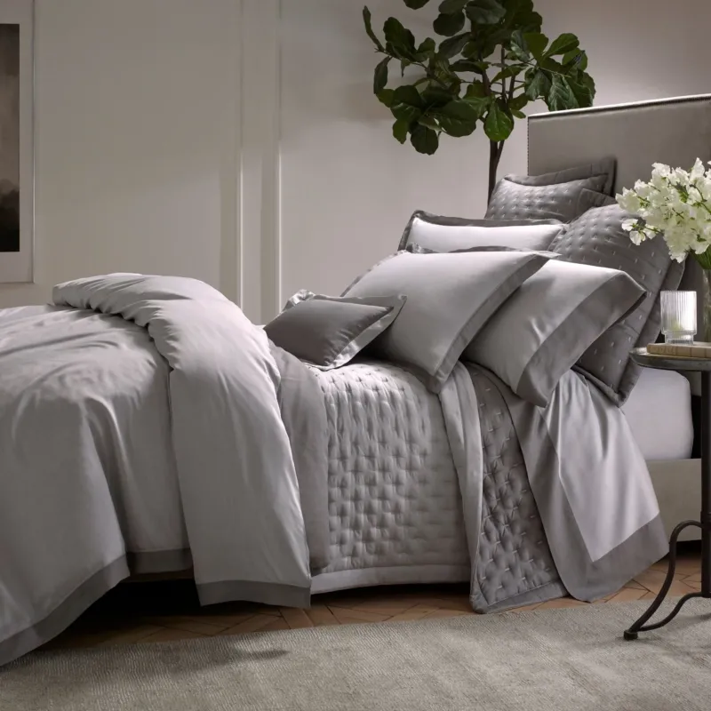Home Treasures Celeste quilted coverlet and euro sham set in silver grey on styled bed.