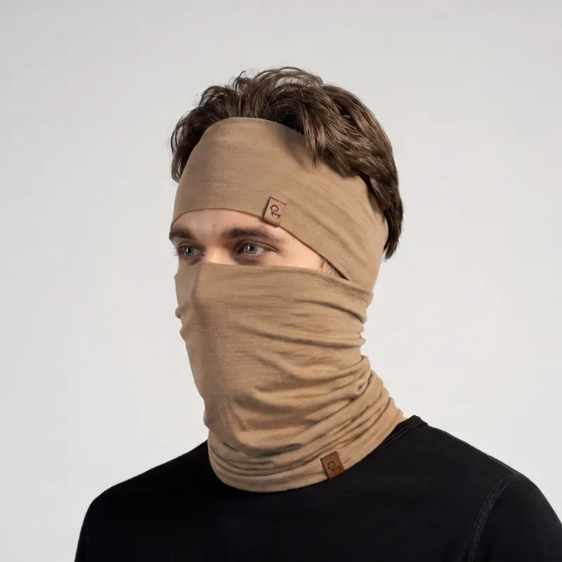 A man looking slightly to the left, wearing a matching beige headband and a neck gaiter pulled up over his nose and mouth, covering the lower half of his face. He has light eyes and brown hair. He is wearing a black long-sleeved top. Both the headband and the gaiter feature a small, rectangular brown leather logo tag. The background is a solid light grey.
