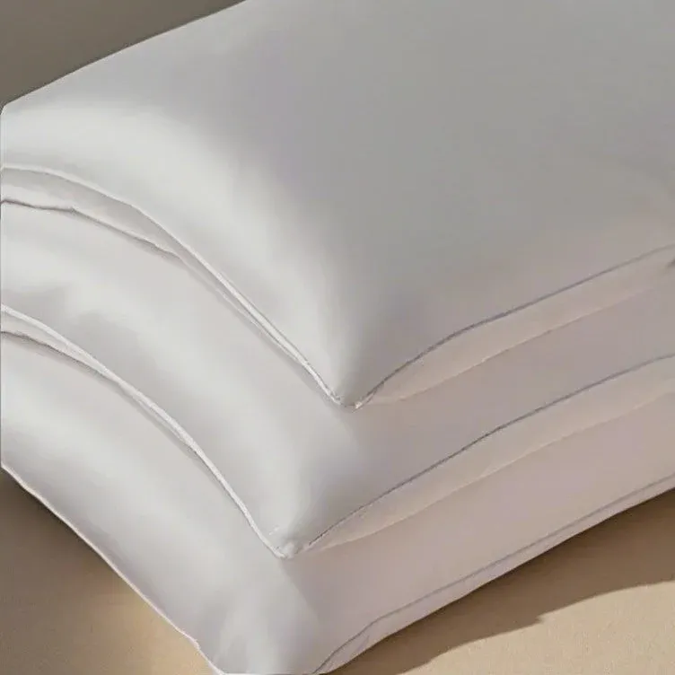 Kumi Kookoon ivory silk-filled pillows stacked, showing lustrous smooth fabric.